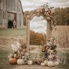 a mirror sitting in the middle of a field with pumpkins and flowers on it