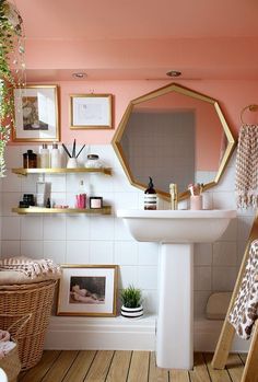 a white sink sitting under a mirror next to a shelf filled with pictures and plants