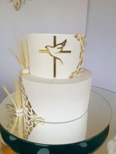 a white cake with gold decorations and a cross on top