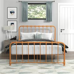 an orange metal bed frame in a bedroom with blue and white decor on the walls