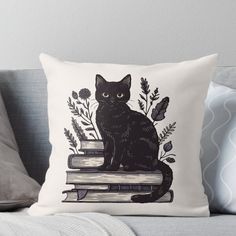 a black cat sitting on top of books with flowers and leaves around it throw pillow