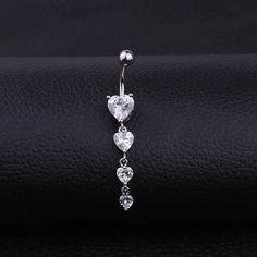 a heart shaped dangling belly ring with three crystal hearts on it's back end