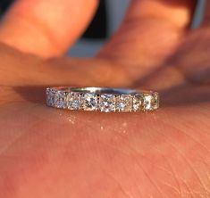 a woman's hand with a wedding band on it and the ring has five diamonds