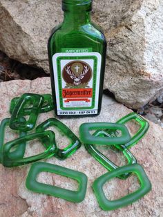 a green bottle sitting on top of a rock next to some metal links and chains