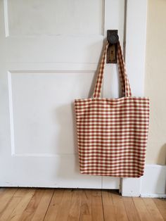 a brown and white checkered tote bag hanging from a hook on a door