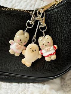 three small key chains are attached to a black purse