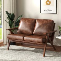 a brown leather couch sitting on top of a wooden frame in a living room next to a potted plant