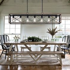 a dining room table with four chairs and a bench in front of the table is surrounded by windows