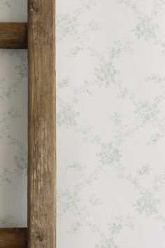 an old wooden frame against a wall with floral wallpaper on the walls behind it