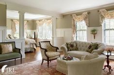 a living room filled with lots of furniture next to two windows covered in drapes