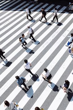 many people are walking across the crosswalk