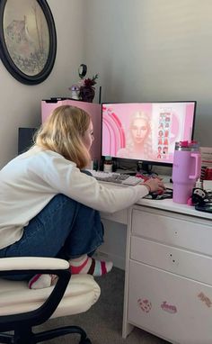 a woman sitting at a desk with a computer on her lap and looking at the screen