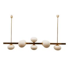 an overhead light fixture with five white balls hanging from it's brass frame and four gold poles