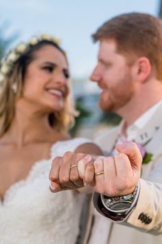 a bride and groom posing for the camera with their wedding rings in front of them