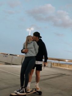 a man and woman are kissing on a skateboard