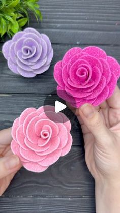 three pink and purple paper flowers being held by someone's hands