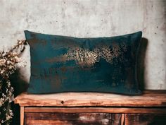 a green pillow sitting on top of a wooden table next to a vase with flowers