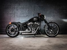 a black motorcycle parked in front of a brick wall with lights on it's side