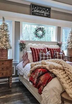 a bedroom decorated for christmas with red and white decorations on the windowsill, plaid bedding, and wreaths