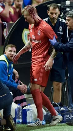 the soccer player is being stretchered off on the field by an injured man with blood all over his face