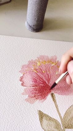 someone is painting a flower with watercolors on paper