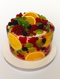 a cake decorated with fruit and berries on a white plate, ready to be eaten