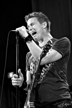 a man singing into a microphone while holding a guitar