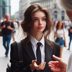 a woman in a suit and tie talking to another person on the side of the street