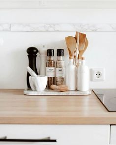 spices and utensils are sitting on a counter top in a kitchen with white walls