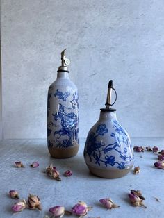 two blue and white vases sitting on top of a table next to dried flowers