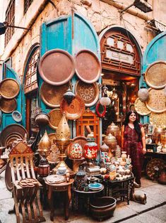 a woman standing in front of a store filled with lots of pots and pans