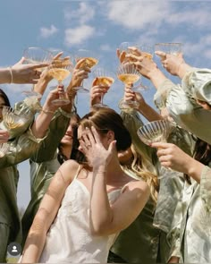 a group of women holding wine glasses up to their faces with the sky in the background