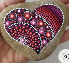 a hand holding a painted rock in the shape of a heart