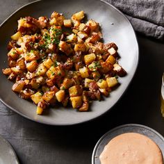 a plate full of potatoes and sauce on a table with other dishes to the side