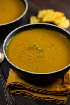 two bowls filled with soup on top of a wooden table next to silver spoons