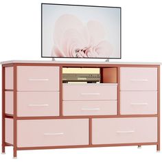 a flat screen tv sitting on top of a pink dresser next to a white wall