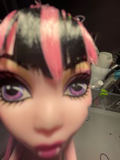 a close up of a doll's face with pink and black hair on it