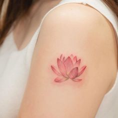 a woman's arm with a pink flower tattoo on the left side of her shoulder