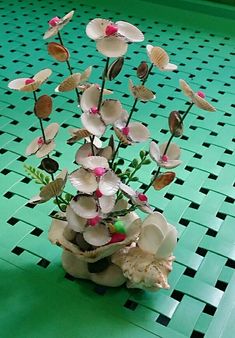 a vase filled with lots of flowers on top of a green table covered in black and white tiles