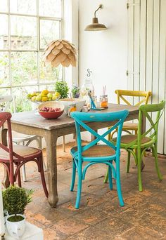 a dining room table with chairs and bowls of fruit on the table next to it