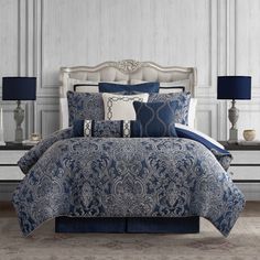 a bed with blue and white comforters in a room next to two nightstands