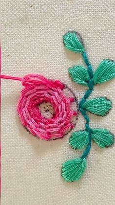 a close up of a piece of yarn with a flower on it and a needle