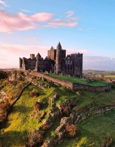 an old castle sitting on top of a lush green hillside