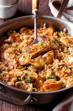 chicken and rice in a skillet with a ladle