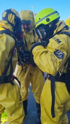 two firemen in yellow suits and helmets are talking to each other while wearing breathing apparatuss