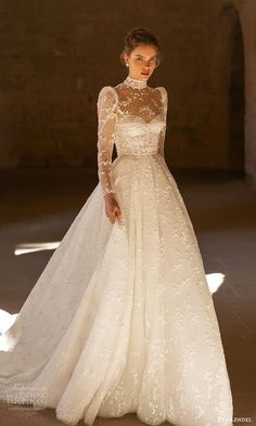 a woman in a white wedding dress with sheer sleeves and a long train on the runway