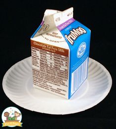 a carton of milk sitting on top of a paper plate with a black background