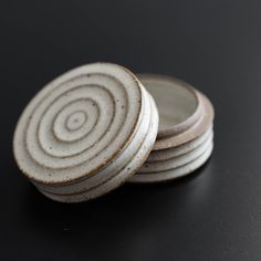 three white coasters stacked on top of each other in front of a black background