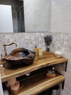 a bathroom sink sitting on top of a wooden shelf next to a mirror and vase