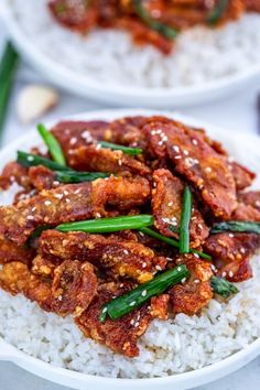 two white plates filled with rice and meat on top of each other, next to chopsticks